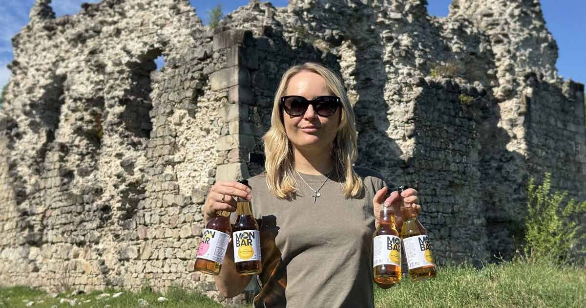 Яна Матвійчук - засновниця бренду Monbar - тримає власний сидр яблучний на тлі Середнянського замку тамплієрів